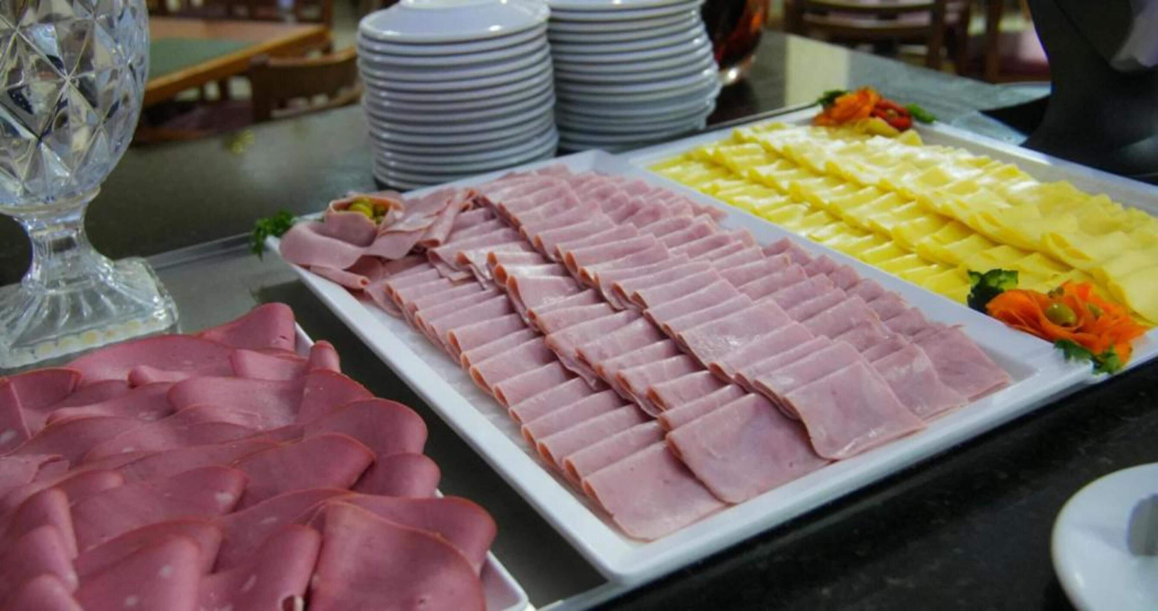 A buffet table with neatly arranged slices of ham and pineapple.