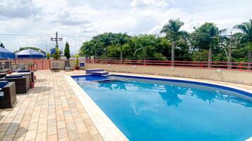 Une piscine dotée d’une terrasse carrelée, de garde-corps de sécurité rouges et de mobilier d’extérieur.