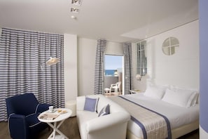 A modern hotel room with a large bed, a desk, a chair, and a view of the sea through the window. - Panorama (Cattolica)