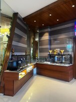 A modern buffet setup with a wooden counter, glass display cases, and a ceiling with recessed lighting.