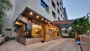 A modern building with a brick facade, large windows, and a covered entrance area. - Hotel Suba International (Mumbai)
