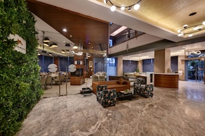 A modern lobby with a reception desk, seating area, and a glass wall. - Hotel Suba International (Mumbai)