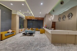A modern lobby with a reception desk, seating area, and wall clocks.