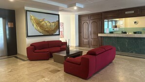 Un área de recepción con mostrador, una obra de arte enmarcada y un sofá rojo.
