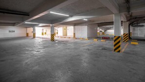 Un estacionamiento vacío con pisos de concreto, pilares con franjas amarillas y negras, y un letrero que dice 'SALIDA'.