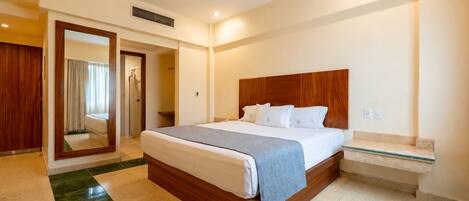 Una habitación de hotel con una cama grande, un cabecero de madera, una mesita de noche y un espejo.