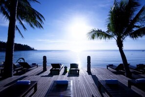 Na praia, areia branca, espreguiçadeiras, guarda-sóis 