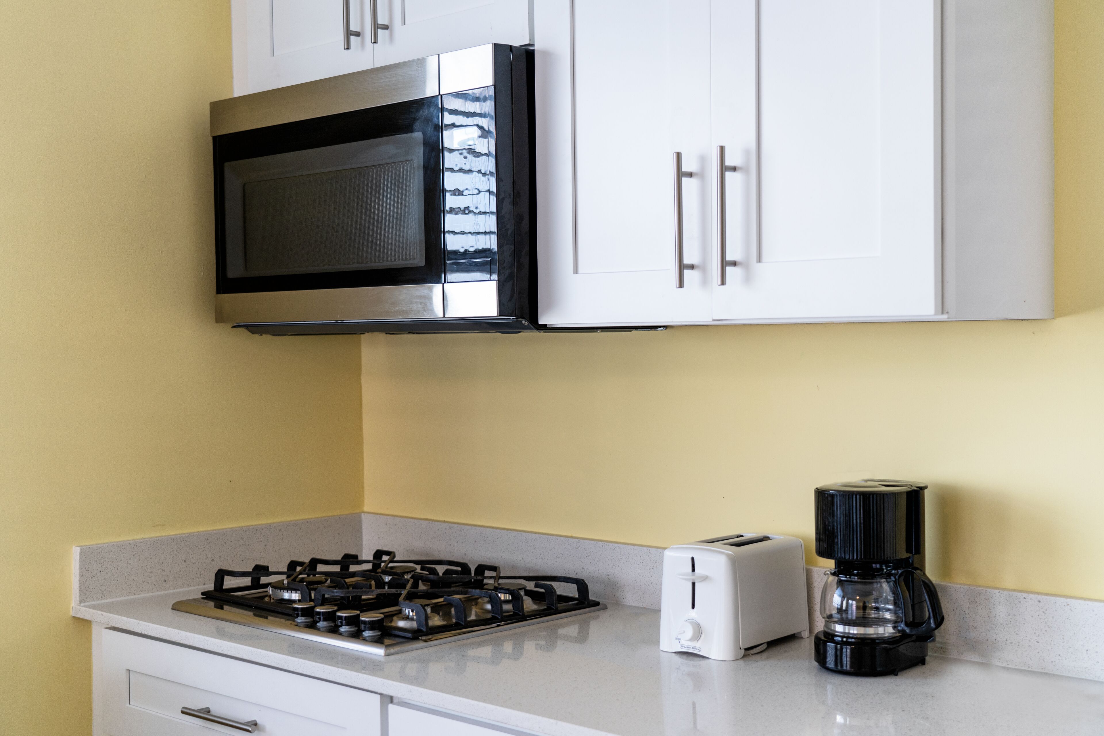 A kitchen with a gas stove, a toaster, and a coffee maker.