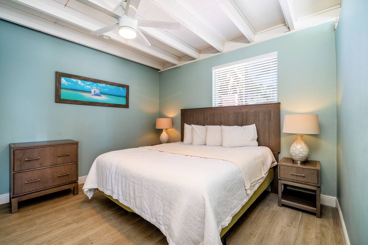 A bedroom with a bed, nightstands, a dresser, and a painting on the wall.
