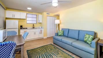 Un espacio habitable compacto con kitchenette, un sofá y un ventilador de techo.