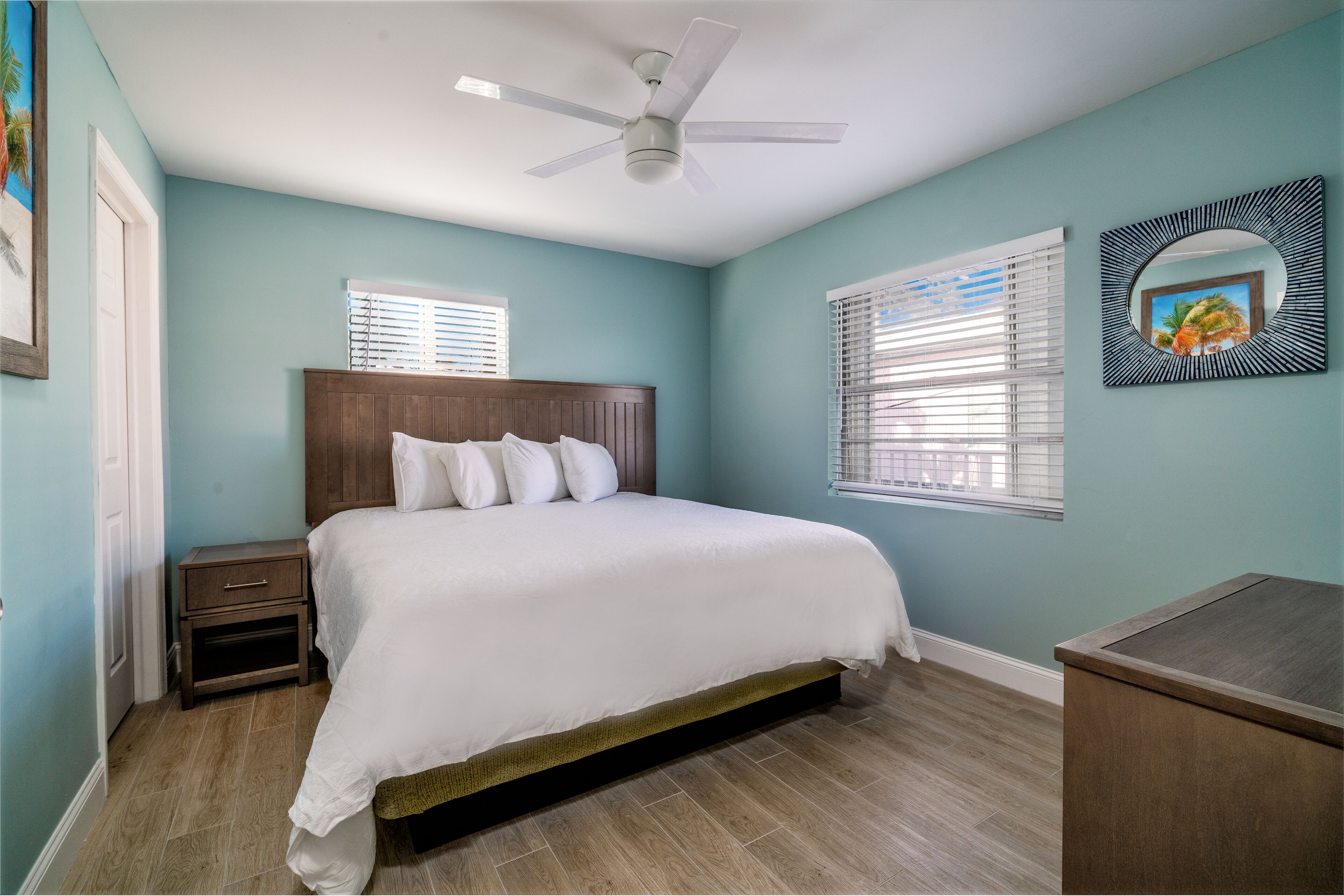 Un dormitorio con cama, mesita de noche, ventilador de techo y escritorio.