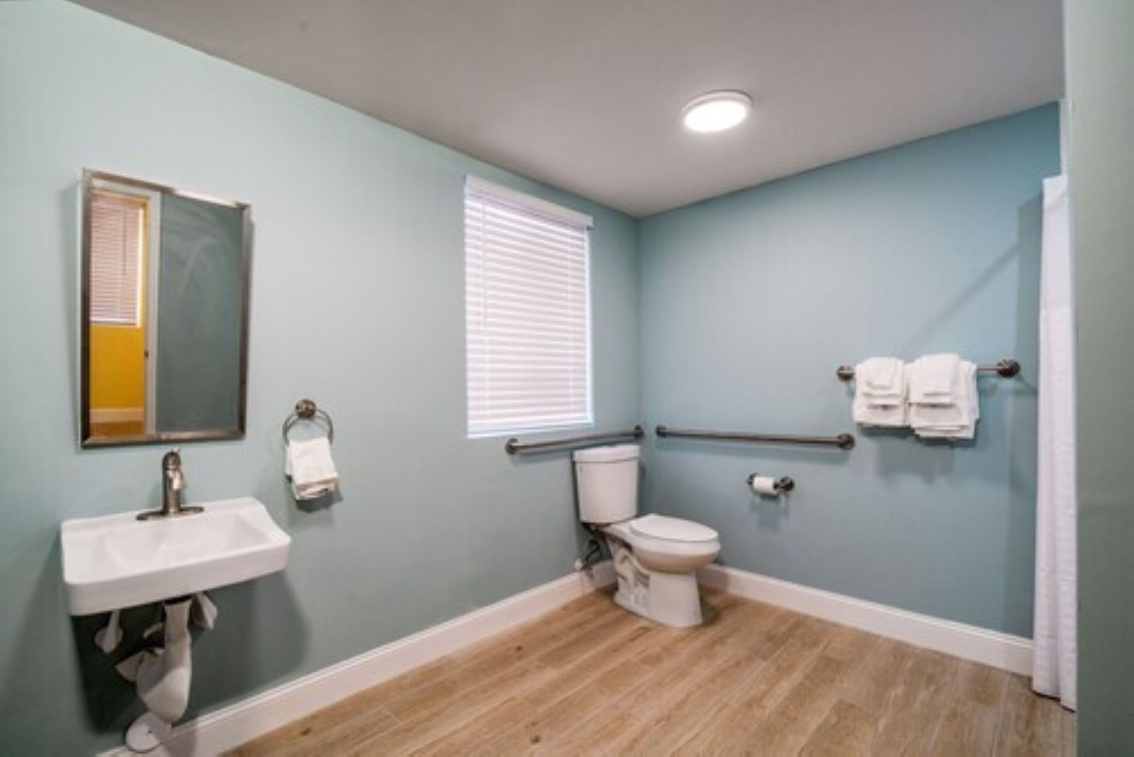 Un baño con lavamanos, inodoro y ventana con persianas.