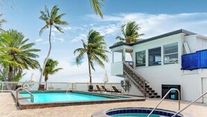 Una piscina con jacuzzi, palmeras y un edificio con escaleras.