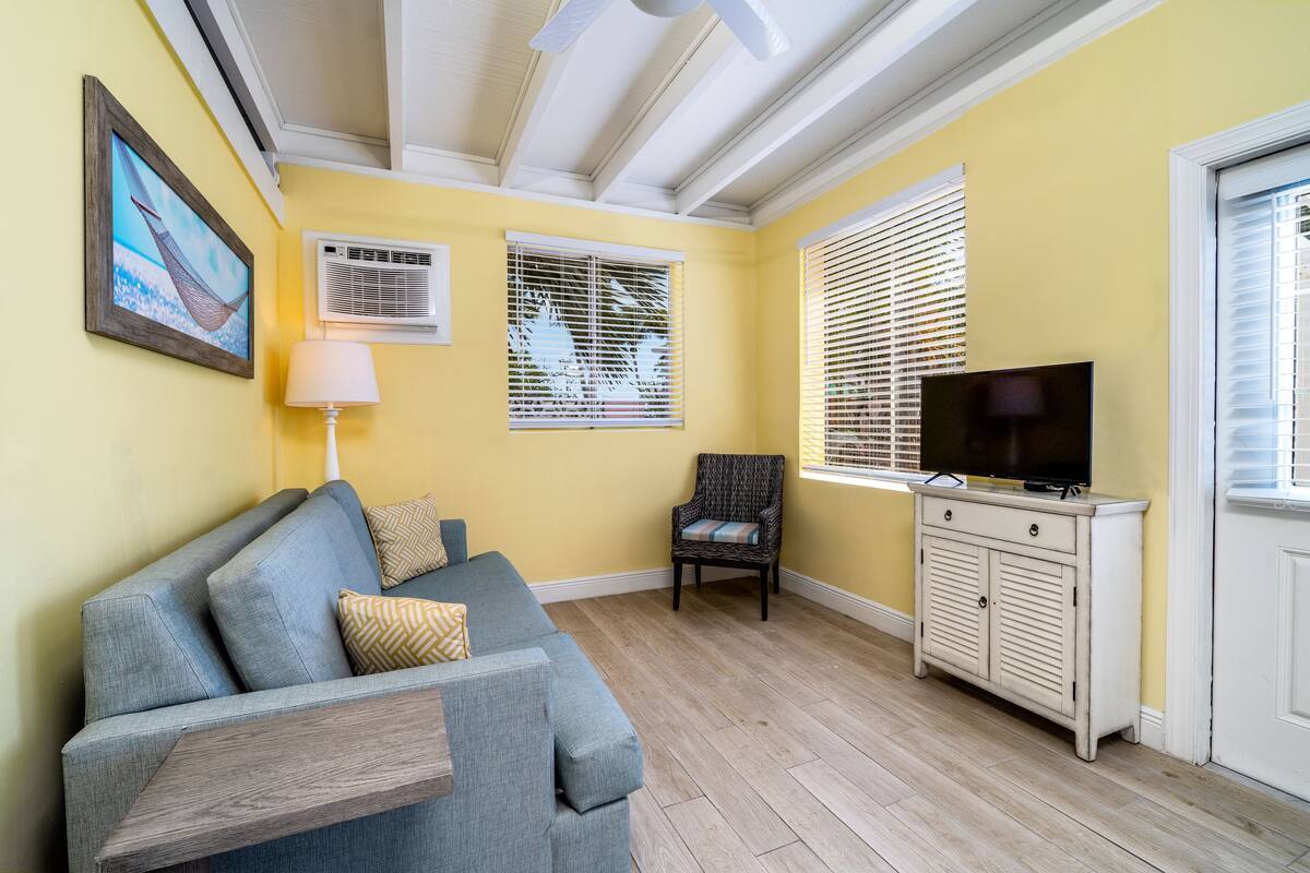 A living room with a sofa, a chair, a TV, and a cabinet.