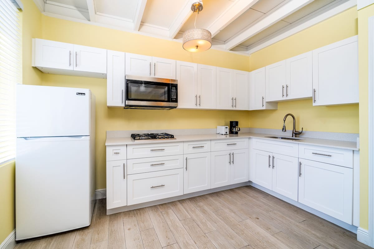 A modern kitchen with white cabinets, a stainless steel microwave, a gas stove, and a sink.
