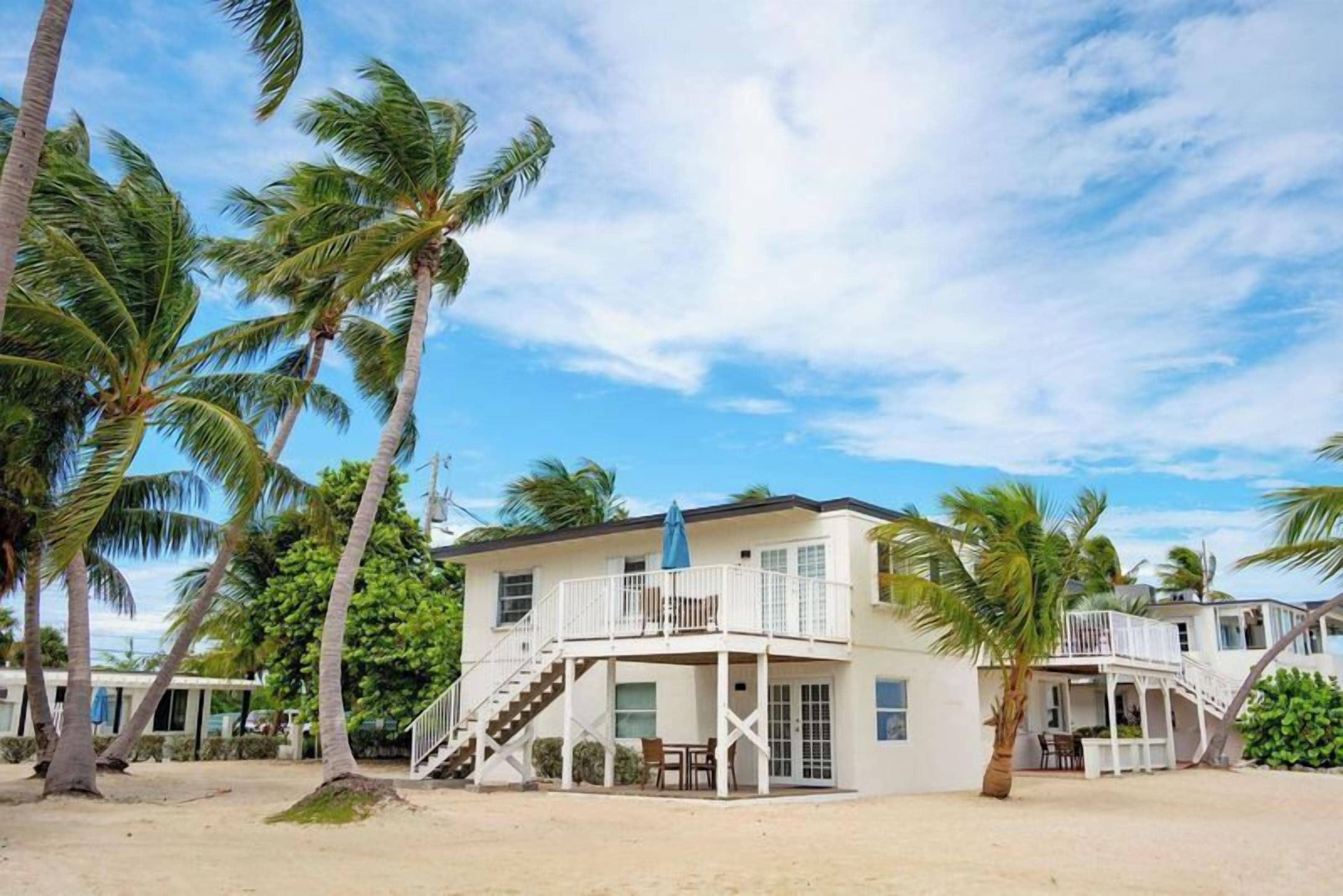 A beachfront property with a two-story building, a balcony, and a staircase leading to the upper level.