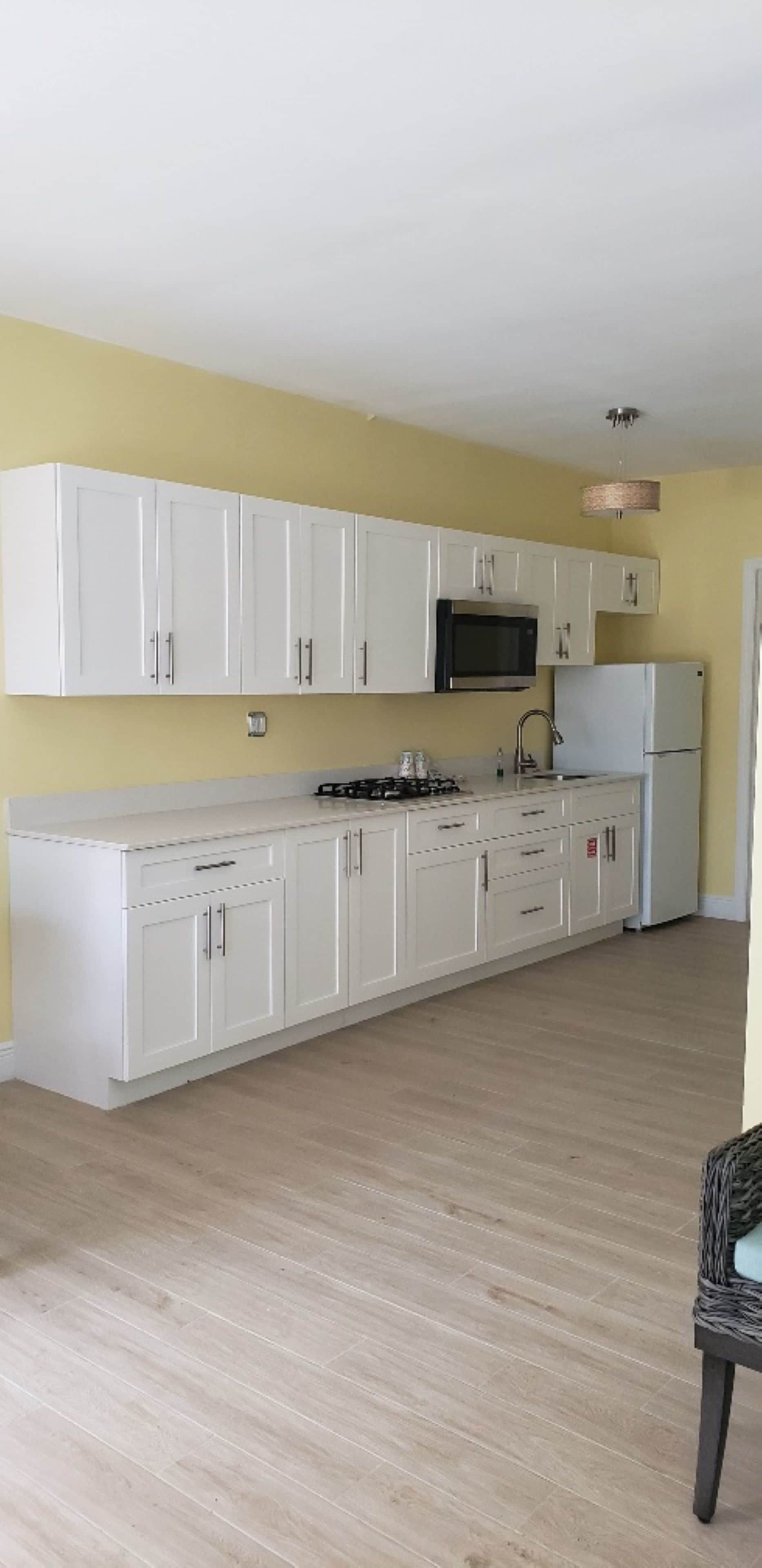 A kitchen with white cabinets, a microwave, a stove, and a refrigerator.