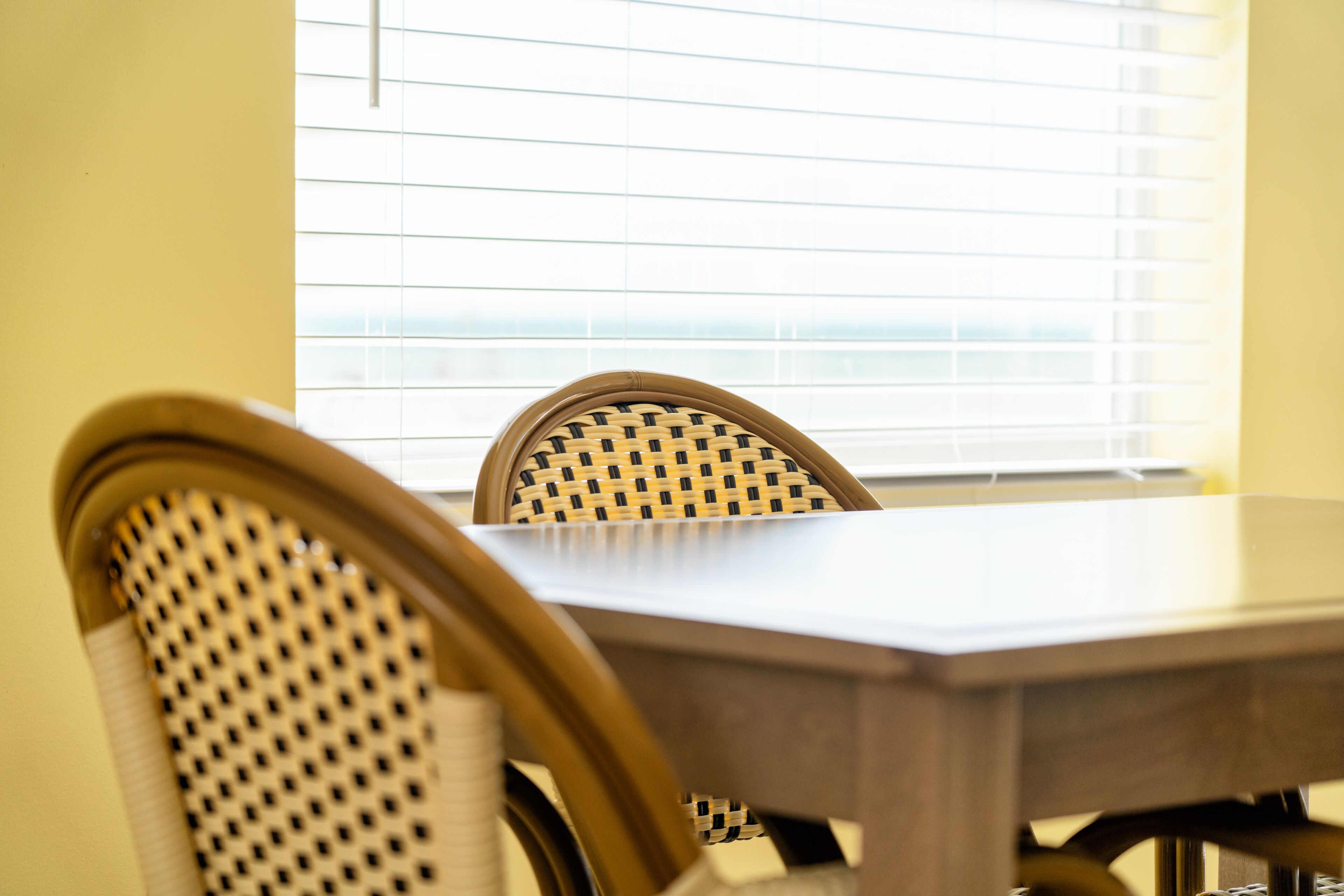A dining area with a wooden table and wicker chairs.