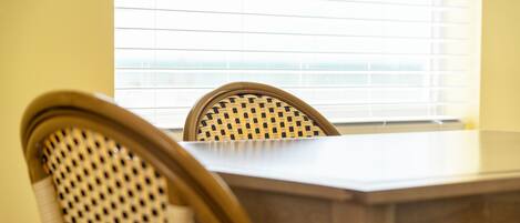 A dining area with a wooden table and wicker chairs.