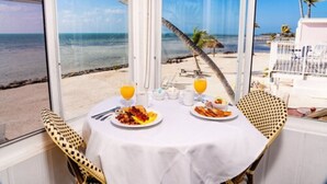 Una mesa con alimentos para el desayuno y vistas a la playa.