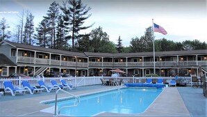 A hotel with a pool, multiple balconies, and a flag. - Mt Madison Inn & Suites (Gorham)