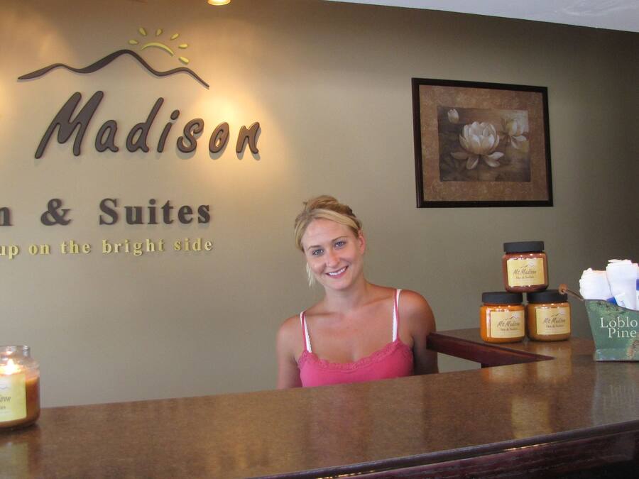 Eine Rezeption im Mt. Madison Inn & Suites mit einem Schild, das den Namen und den Slogan angibt. Auf der Theke stehen Kerzen und Toilettenartikel.