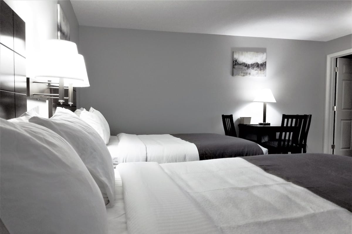 Ein Hotelzimmer mit zwei Betten, einem Schreibtisch und einem Stuhl.