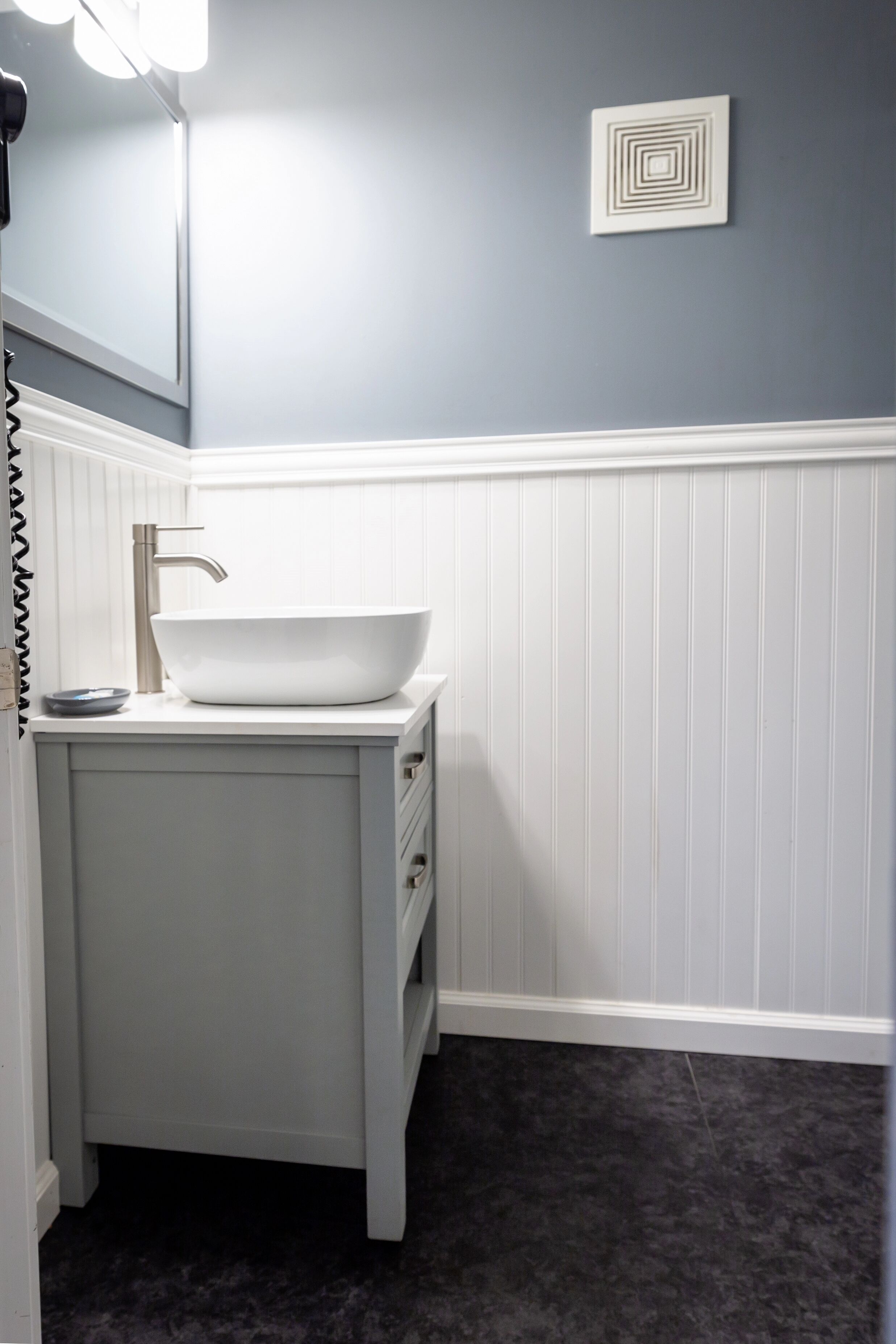 A bathroom with a white vanity, a vessel sink, and a mirror.