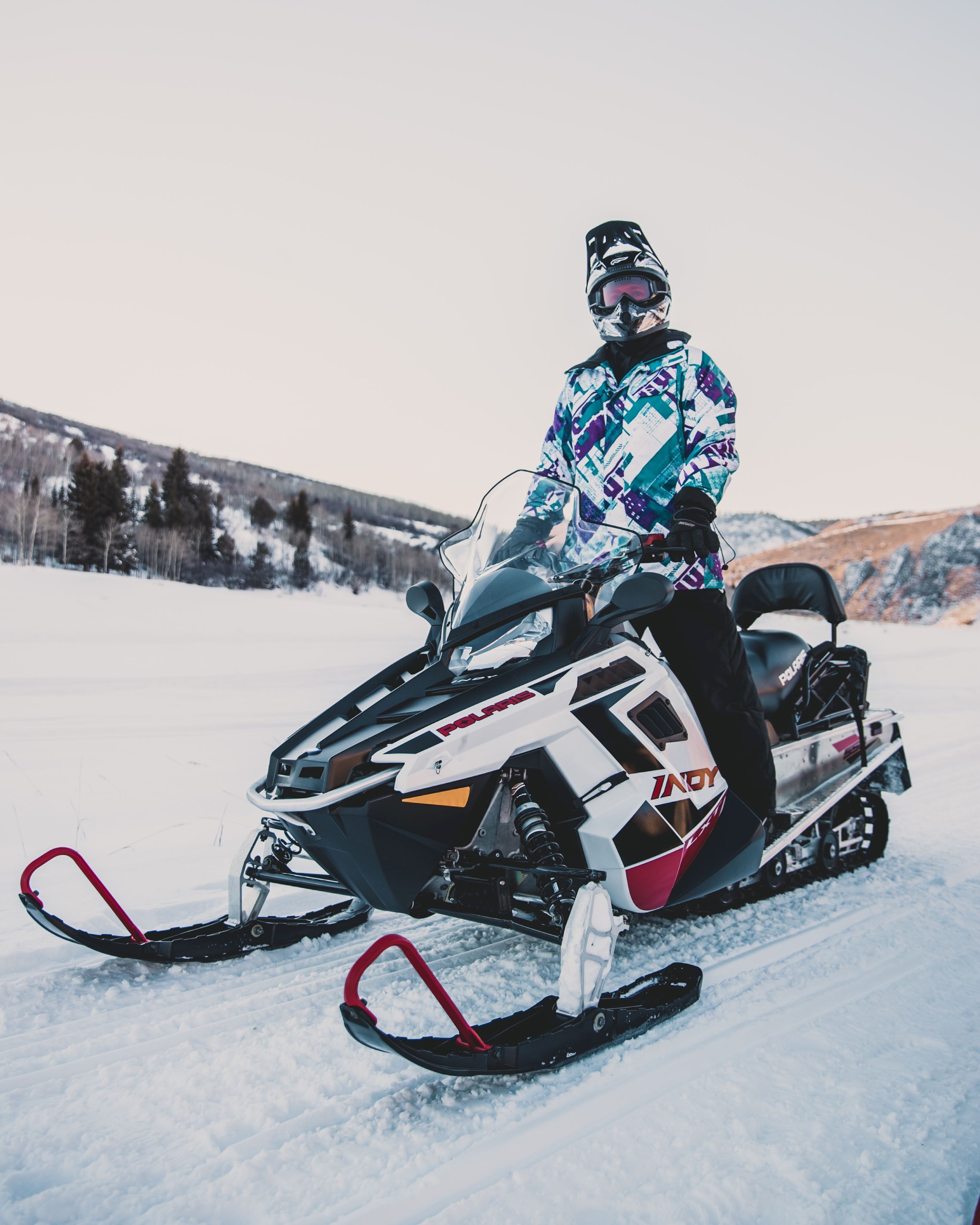 Een sneeuwscooter met een bestuurder in een geruit vest.