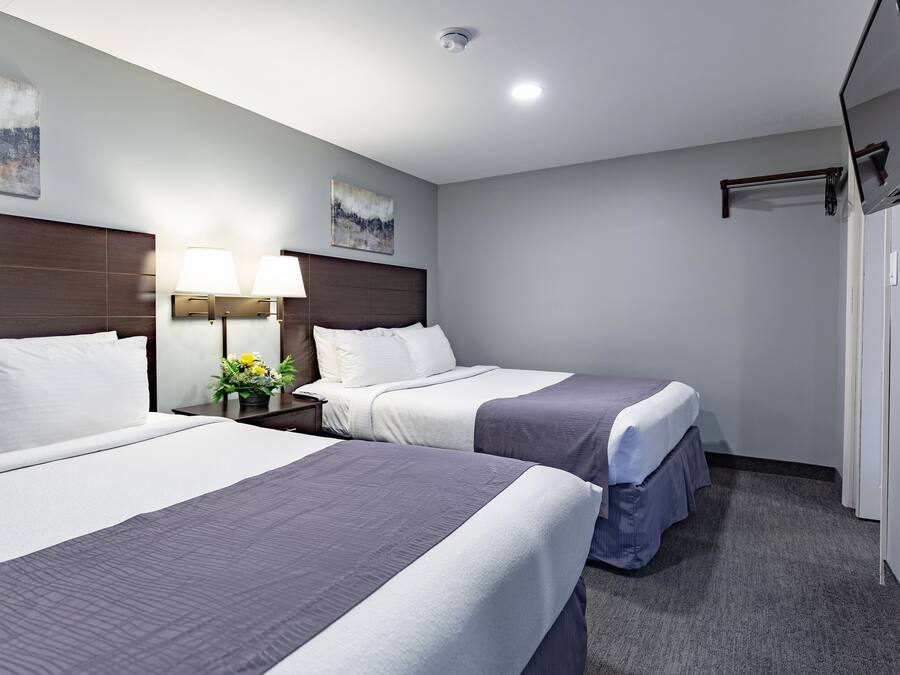 Ein Hotelzimmer mit zwei Betten, einem Nachttisch mit Lampe und einem Gemälde an der Wand.