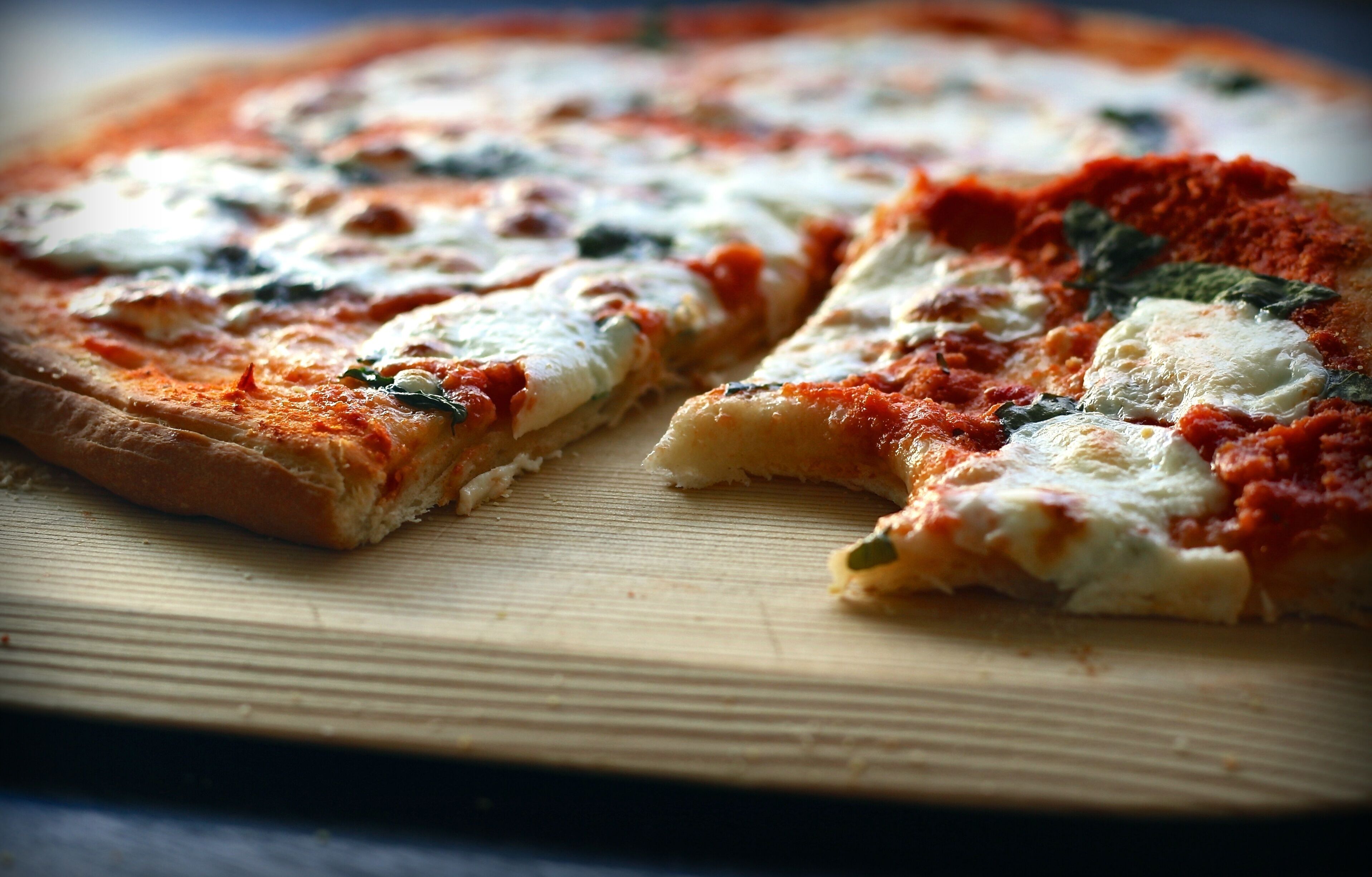 A pizza with cheese and tomato sauce on a wooden cutting board.