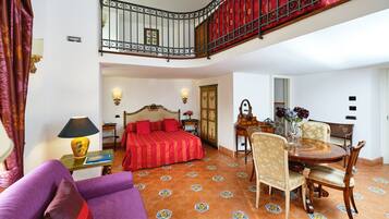 Habitación de hotel con cama, mesa de comedor, sillas, sofá, escalera y baño.
