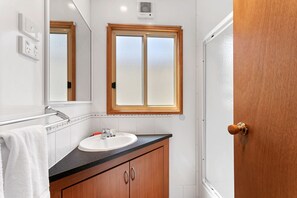A bathroom with a wooden vanity, white sink, and a mirror above it.