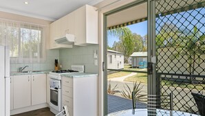 A modern kitchen with white cabinets, a gas stove, and a dining area with a table and chairs. - BIG4 Moama Holiday Park (Moama)