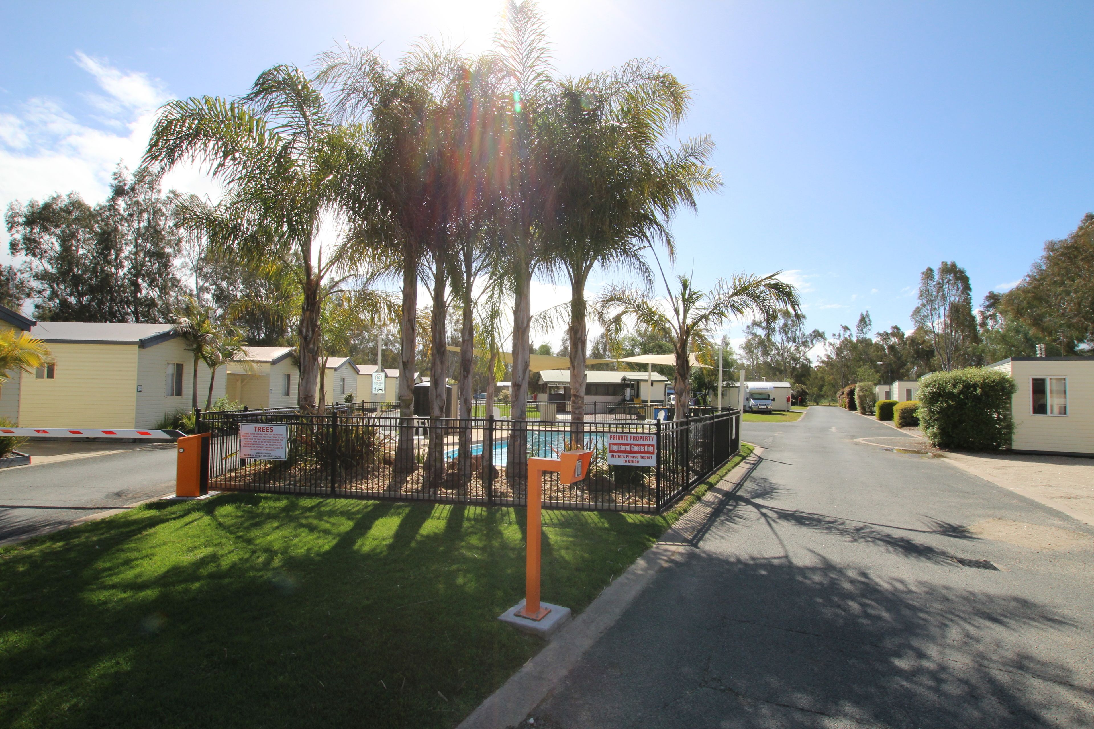 A residential area with mobile homes, a fenced playground, and a clear sky.
