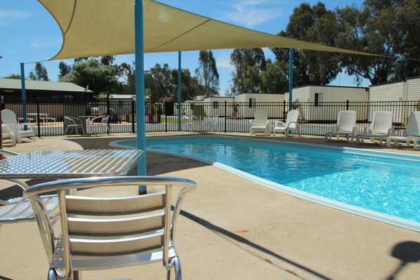 A swimming pool with lounge chairs and a shaded area.