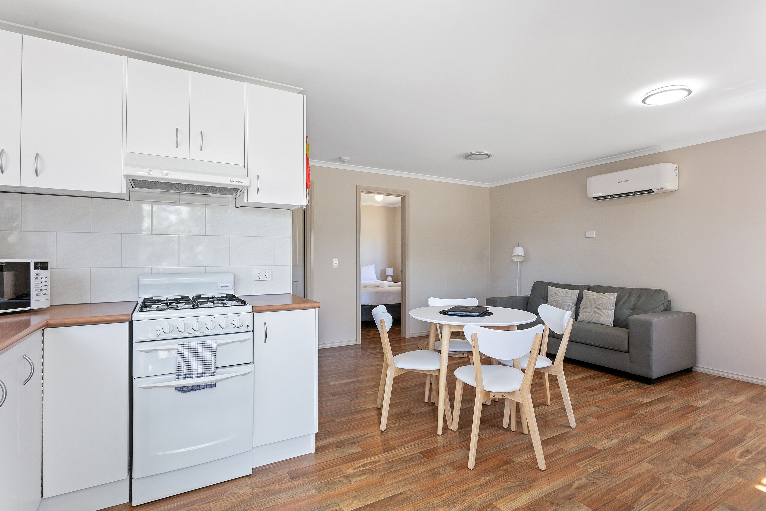A modern kitchen with white cabinets, a stove, and a dining area with a table and chairs.