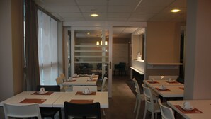 Un restaurant doté de nombreuses tables et chaises, d’un comptoir et offrant une vue à travers une paroi vitrée.