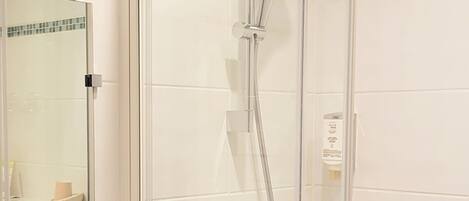 Un baño moderno con cabina de ducha de vidrio, un lavamanos blanco y un salpicadero de azulejos.
