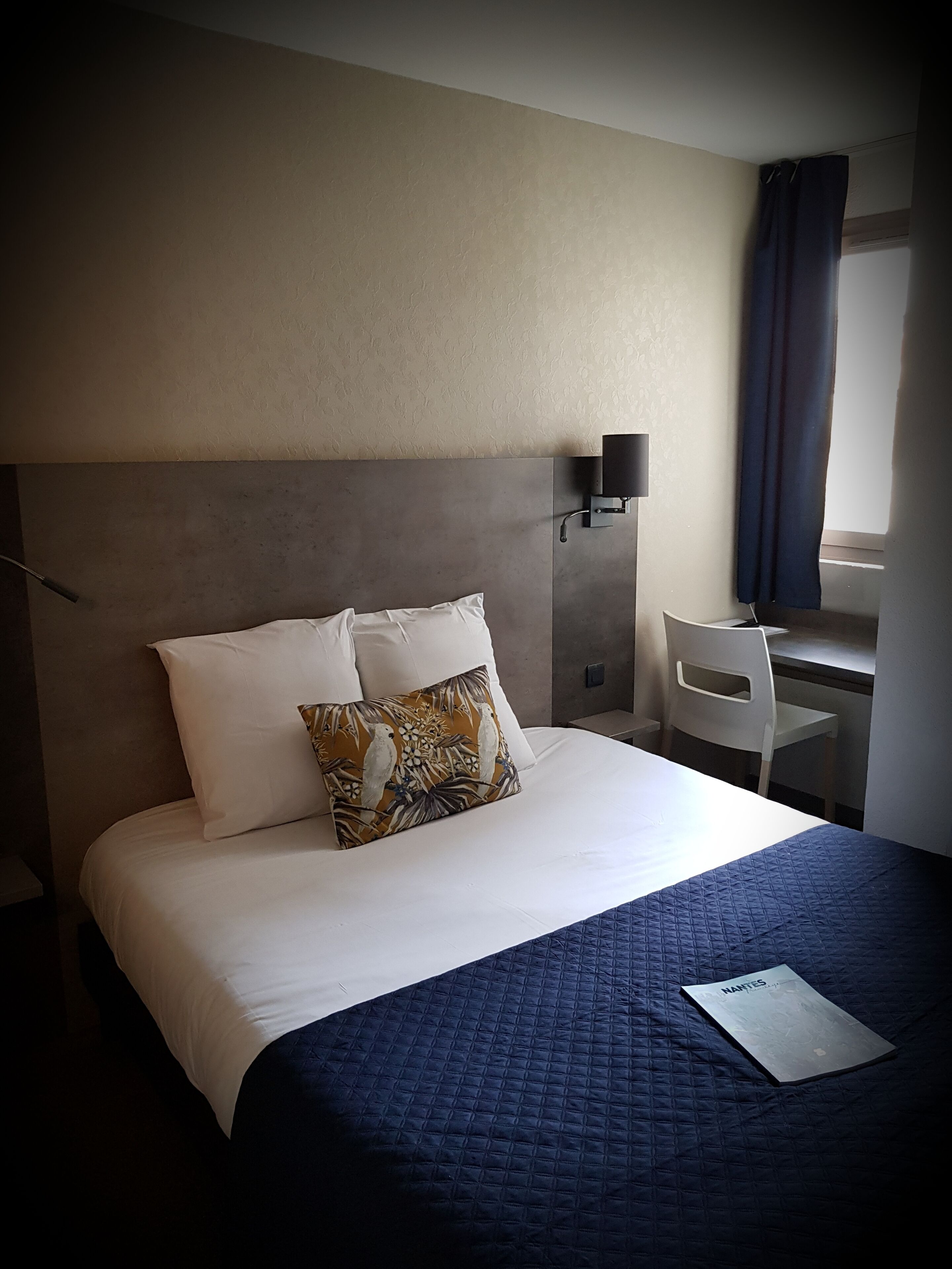 A hotel room with a large bed, a desk, and a chair.
