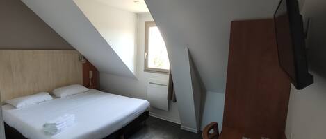 Un dormitorio con cama, escritorio y televisor.