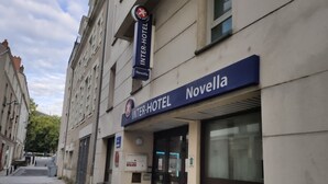 Un bâtiment de la chaîne hôtelière Inter-Hotel, avec une enseigne, une entrée fermée par un portail et un pot de fleurs près de l’entrée.
