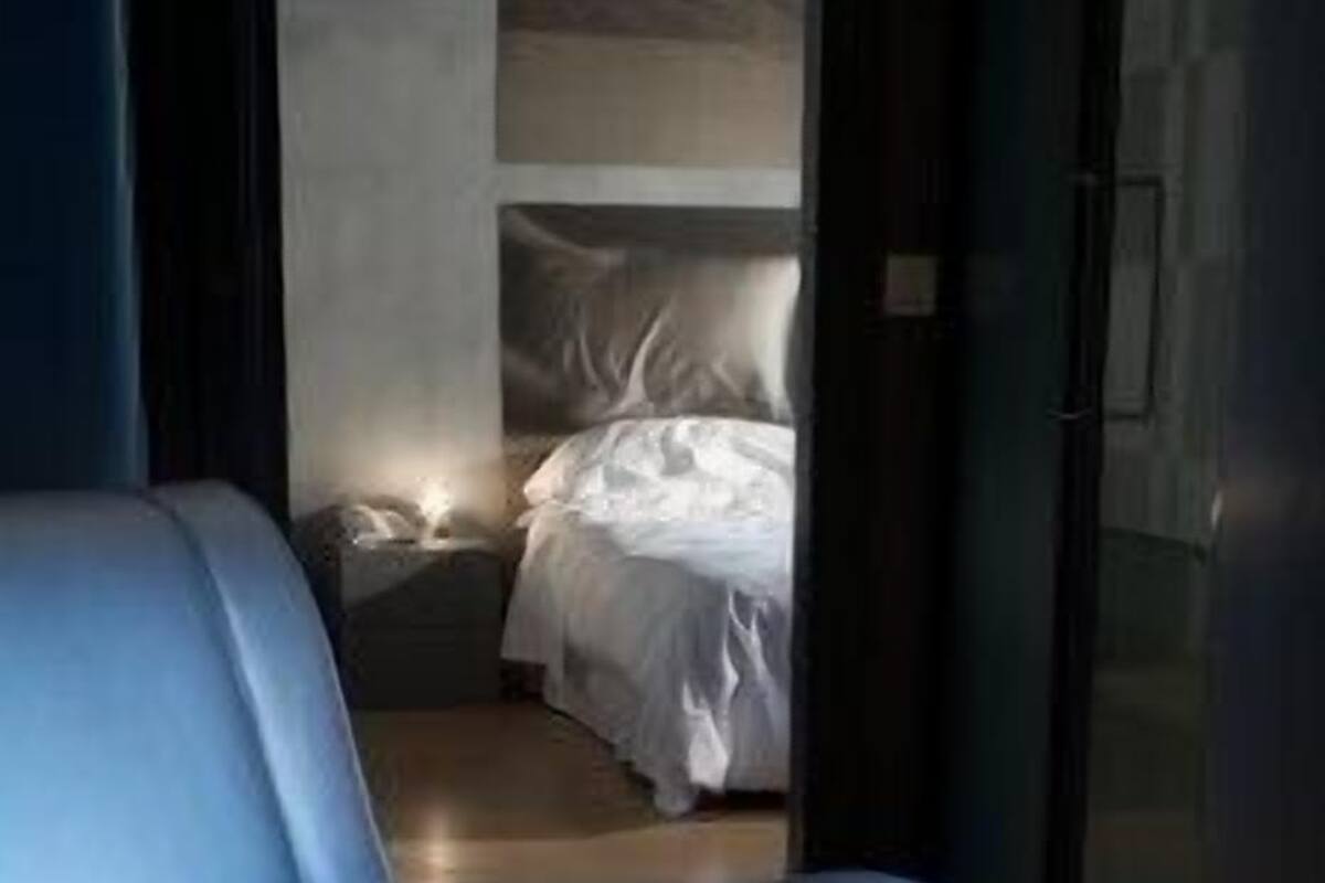 A modern room with a blue sofa, a bed with white bedding, and a small bedside table.