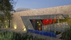 A modern building with a unique angular design, featuring a glass facade and a wooden deck in front. - Balarte Hotel (Modica)