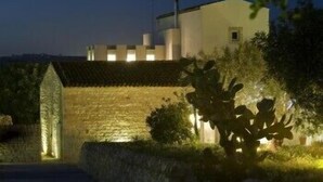 A building with a stone wall and a modern structure with a flat roof. - Balarte Hotel (Modica)