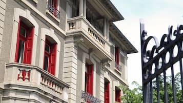 Un edificio histórico con contraventanas rojas y un balcón.