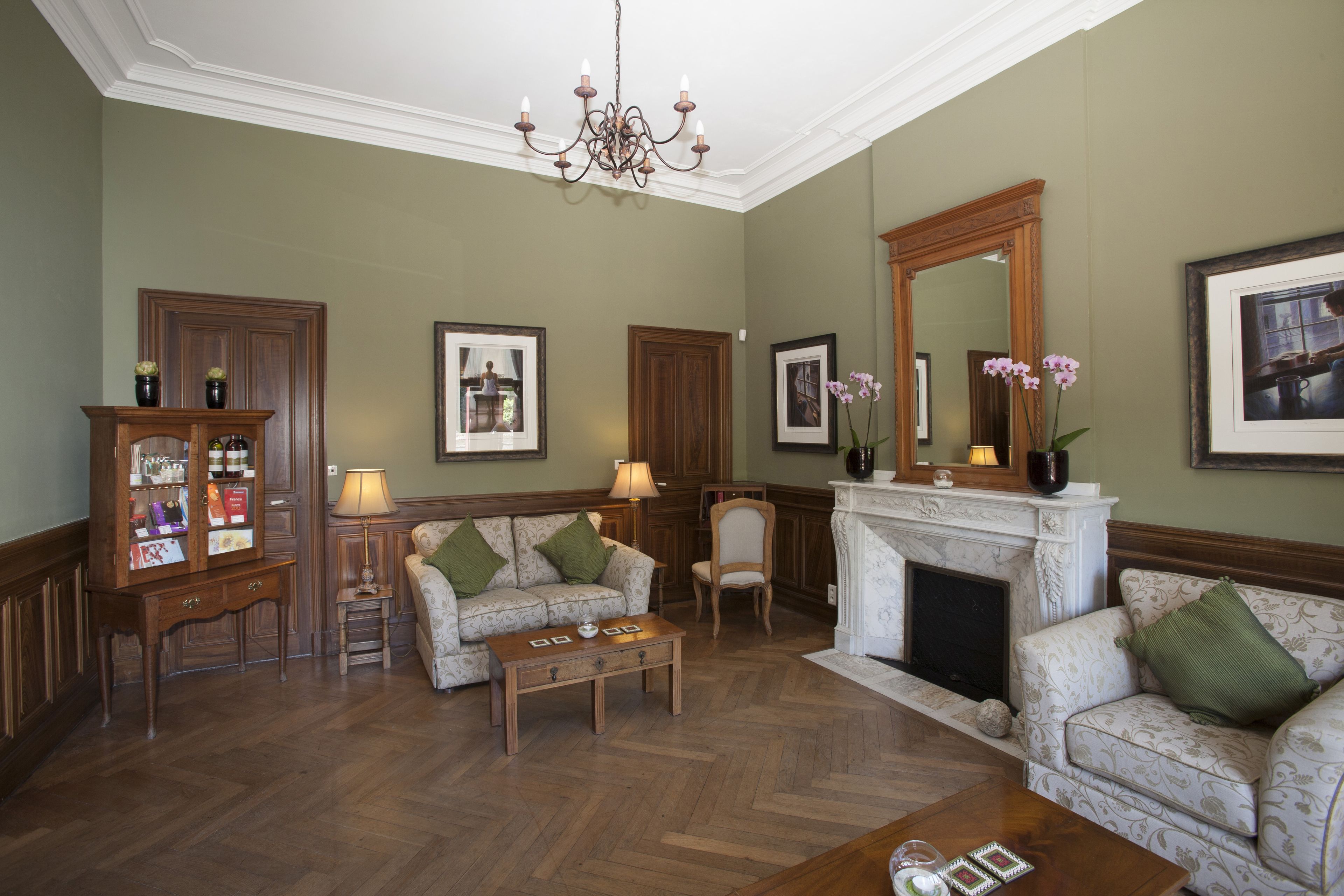 Uma sala de estar com lareira, um candelabro e um armário de madeira.