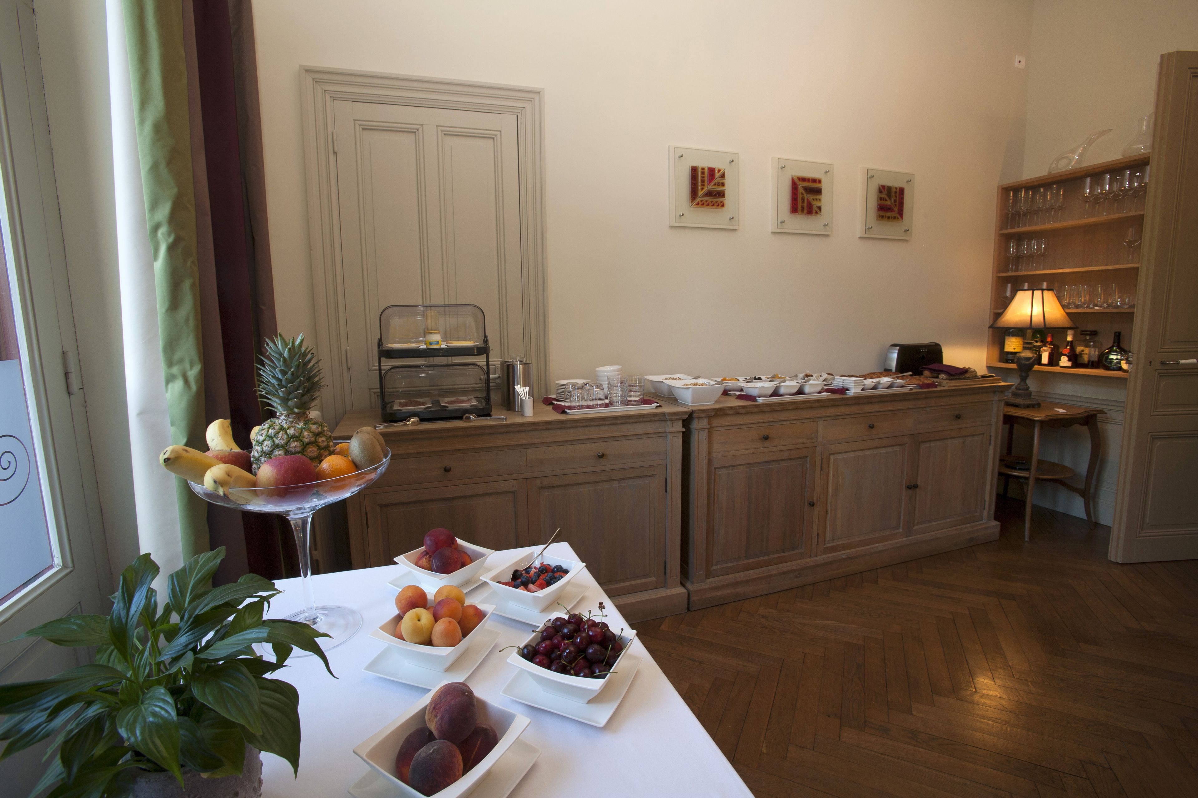 A breakfast buffet with various fruits and a coffee station in a well-lit kitchen area.