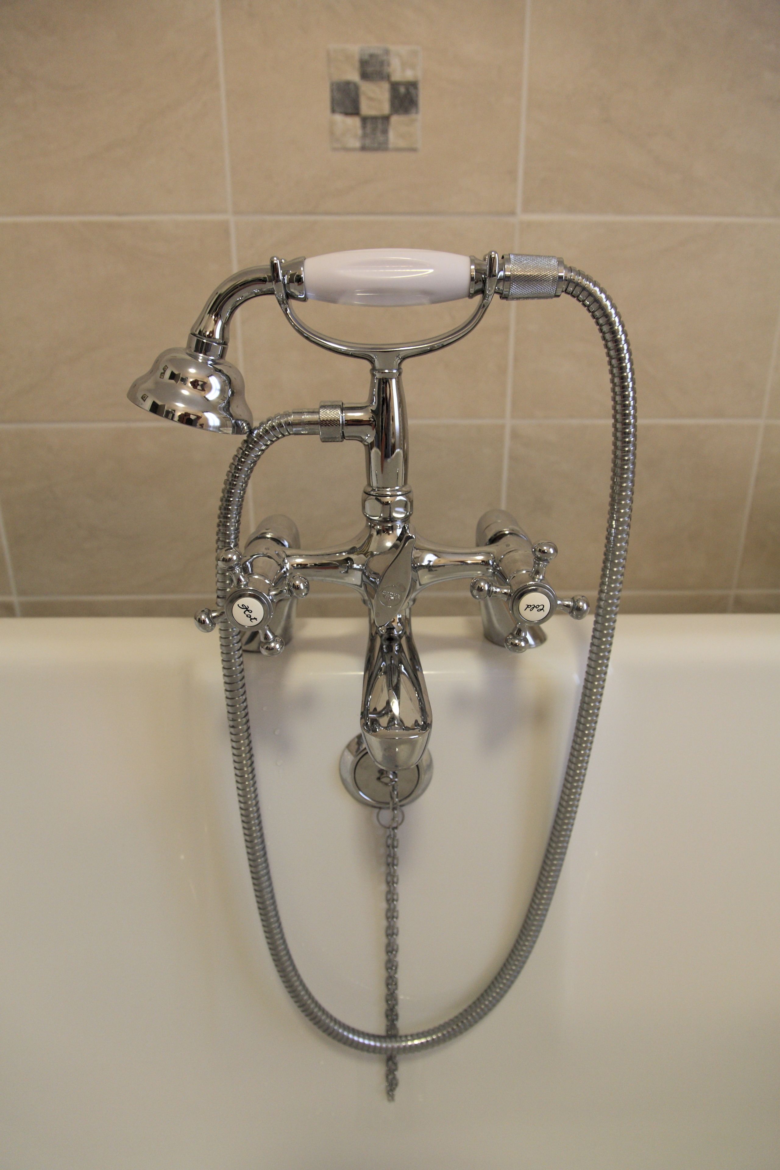 A bathroom with a chrome showerhead, a handheld shower, and a fixed showerhead.