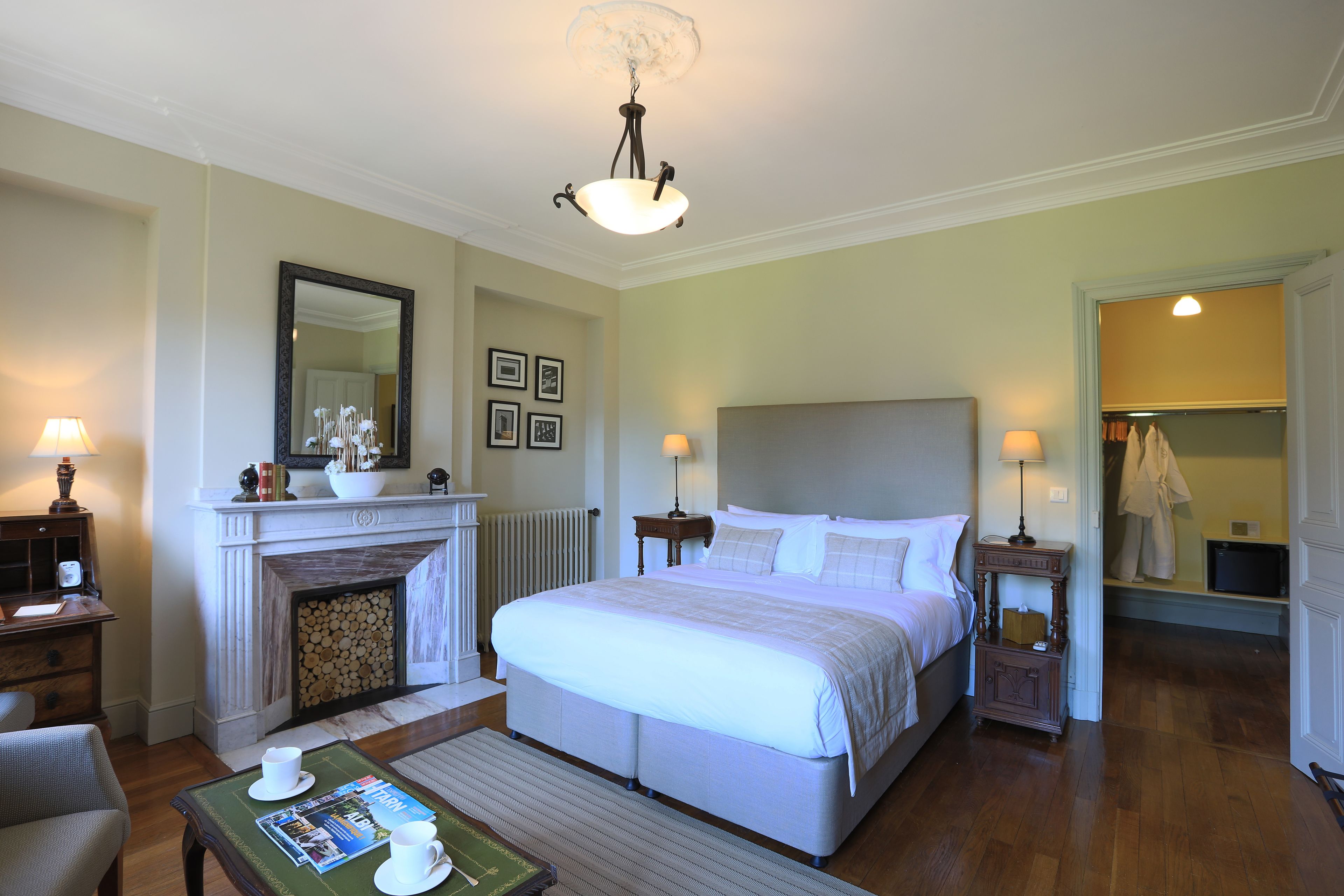A hotel room with a large bed, a fireplace, a mirror, and a walk-in closet.